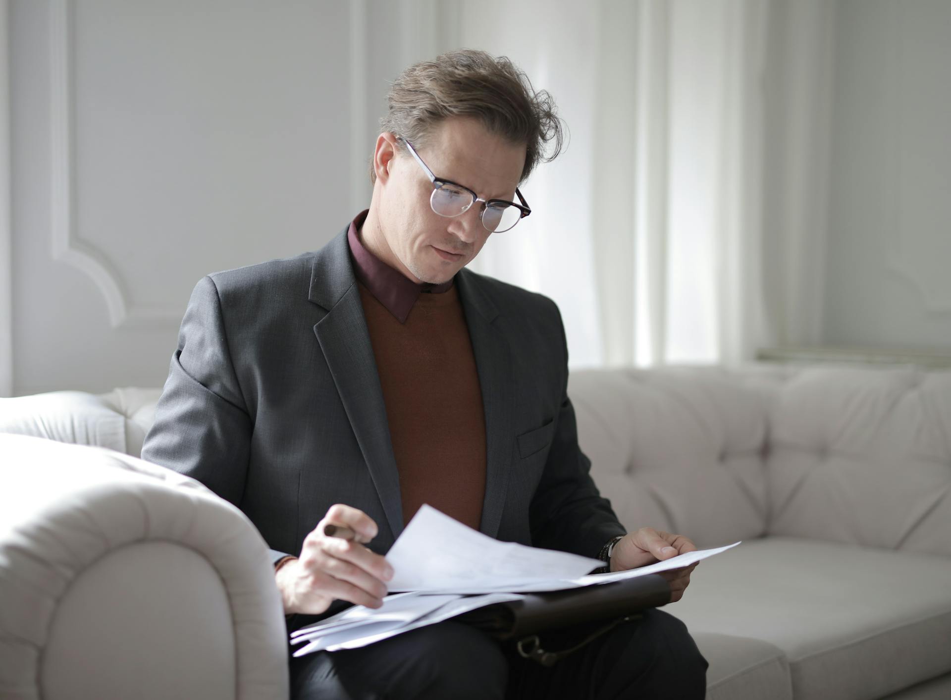 male reading papers on the sofa